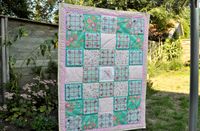 Quilt met gebruik van kledingstof en geborduurd blokken